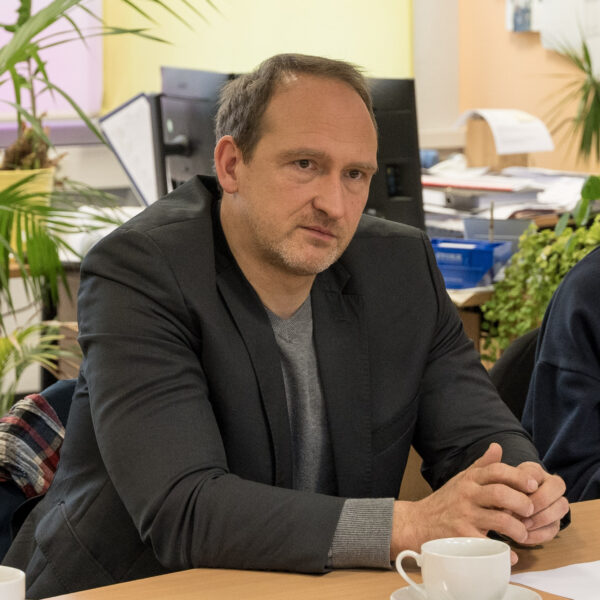 Das Foto zeigt Dr. Falko Grube an einem Besprechungstisch sitzend