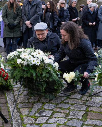 Das Bild zeigt Dr. Falko Grube und Julia Brandt beim Richten der Schleife am Trauerkranz der SPD