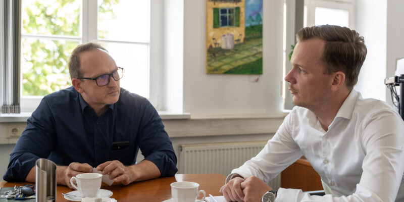 Falko Grube und Alexander Kleine sitzen an einem Besprechungstisch